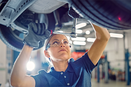 Female mechanic fixing a car on a lift